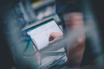 An employee goes through a spreadsheet on his notebook for analysis