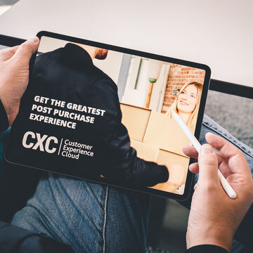 We look over a shoulder at a tablet on which the Customer Experience Cloud is advertised as 