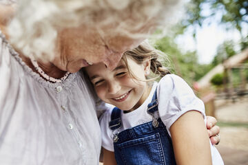 eine gesunde ältere Dame umarmt ein kleines Mädchen, das lächelt