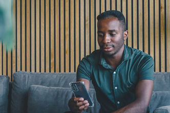 Man in green shirt looks intently at his smartphone