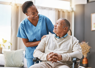 a health care worker and a patient in a wheelchair look at each other with a smile