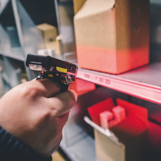 An Arvato employee scans a package with a single finger scanner as part of B2B fulfillment