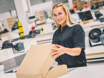 An arvato employee closing a carton of an e-commerce order
