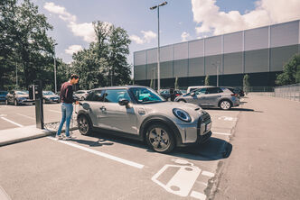 A man charges his electric car in a parking lot