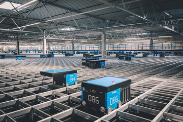 A horizontal autostore grid with robots moving boxes containing consumer electronics items