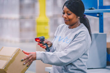 Warehouse employee scanning a package as part of a digital logistics and fulfillment workflow